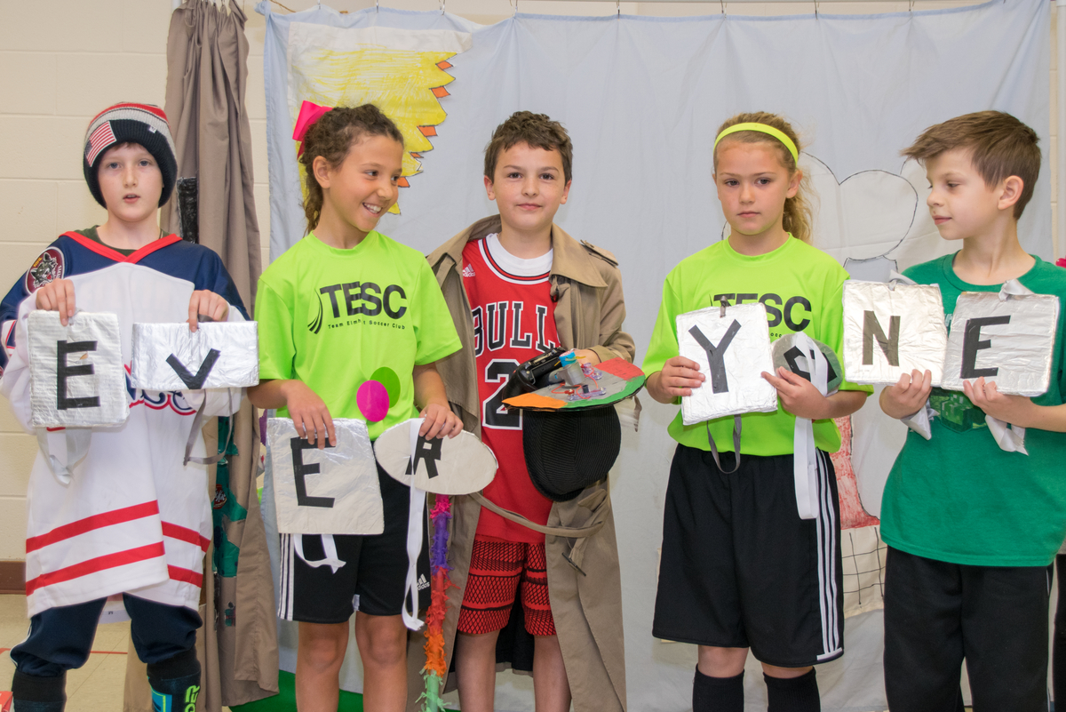 Students performing at a tournament, holding multiple signs that spell "everyone".