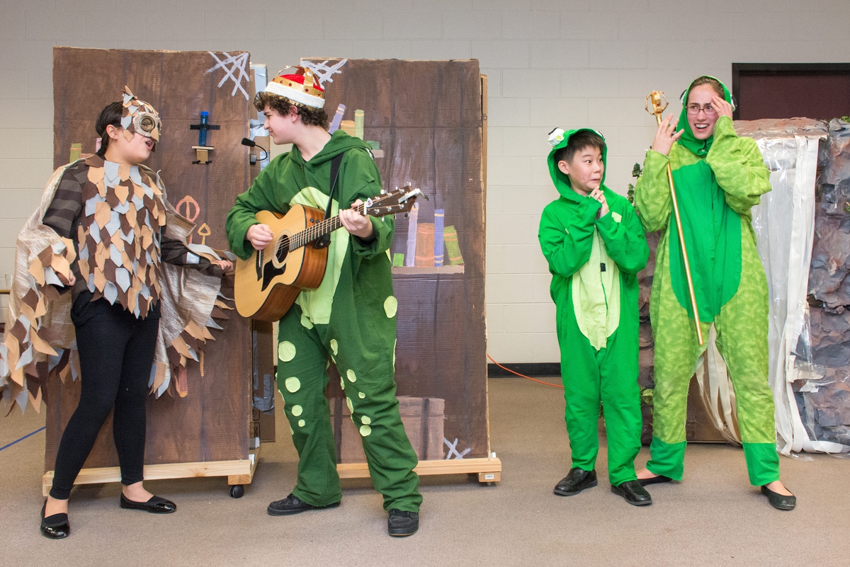 Students performing at a tournament dressed as frogs and an owl